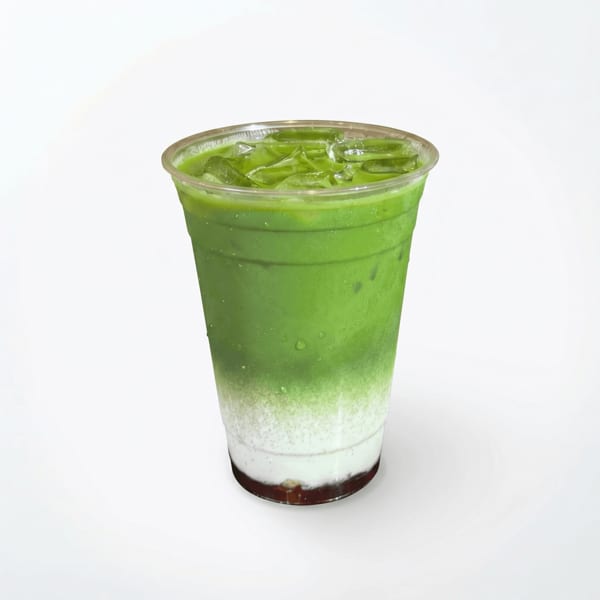 Iced green matcha latte with milk and a dark layer at the bottom in a clear plastic cup.