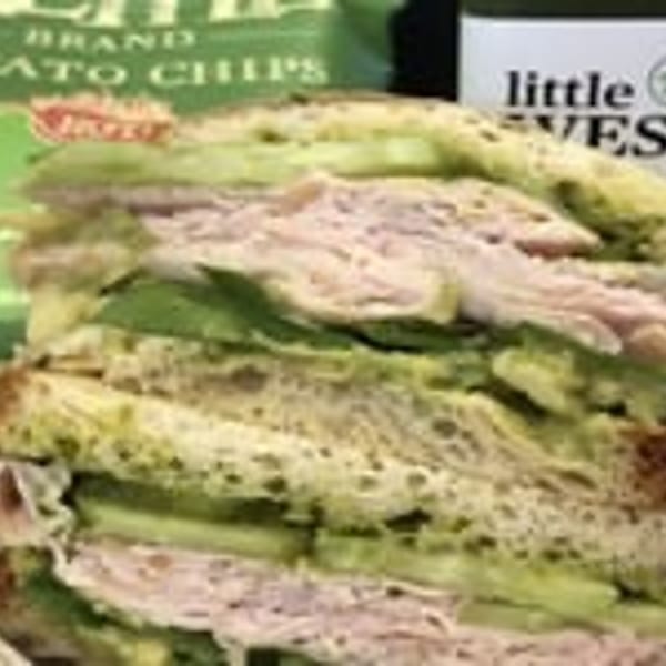Turkey and avocado sandwich with chips and a Little West juice bottle.