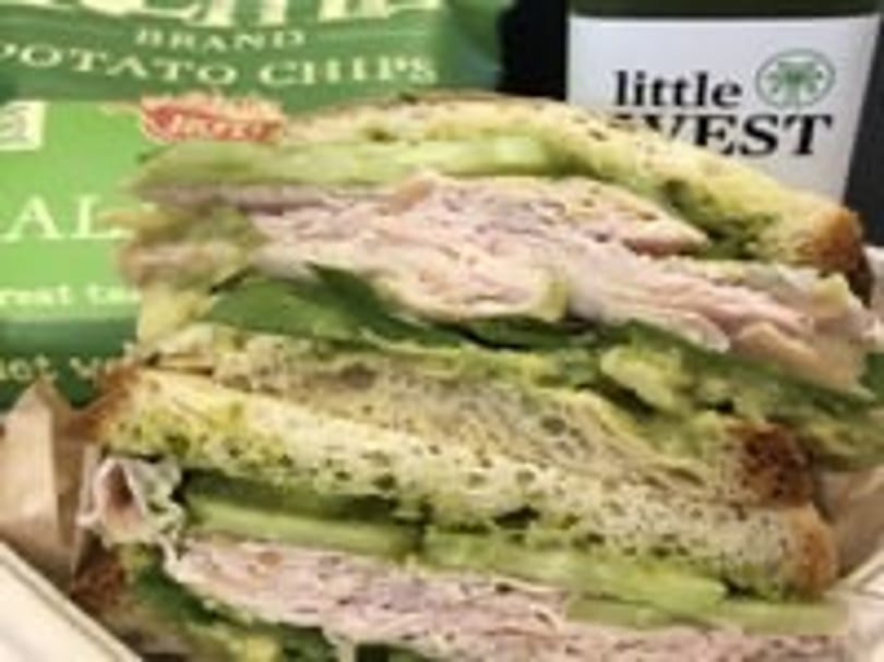 Turkey and avocado sandwich with chips and a Little West juice bottle.